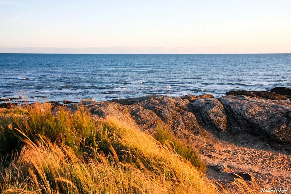 Coucher de soleil doré sur les rochers et l'océan Atlantique à Brétignolles-sur-Mer.