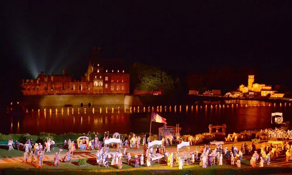Fresque lumineuse, projections et acteurs sur l'immense scène extérieure de la Cinéscénie du Puy du Fou la nuit