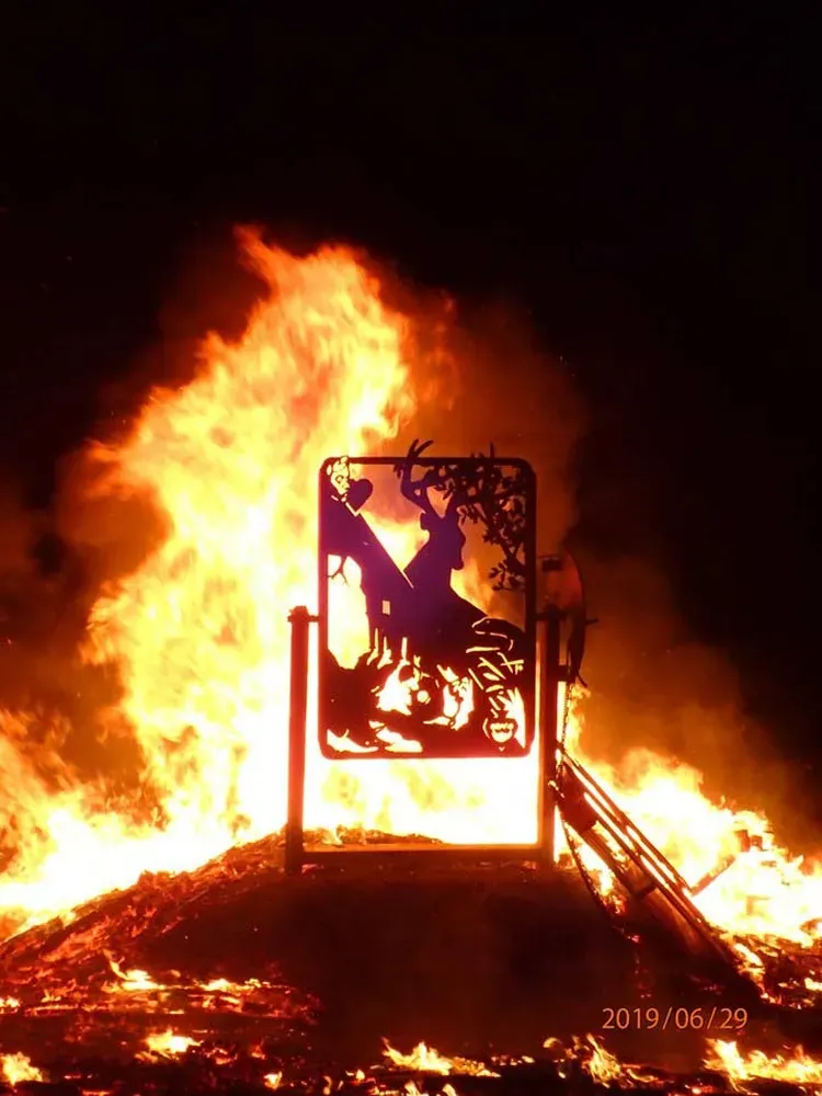 Grand bûcher s'enflammant à la tombée de la nuit lors de la fête traditionnelle à Martinet