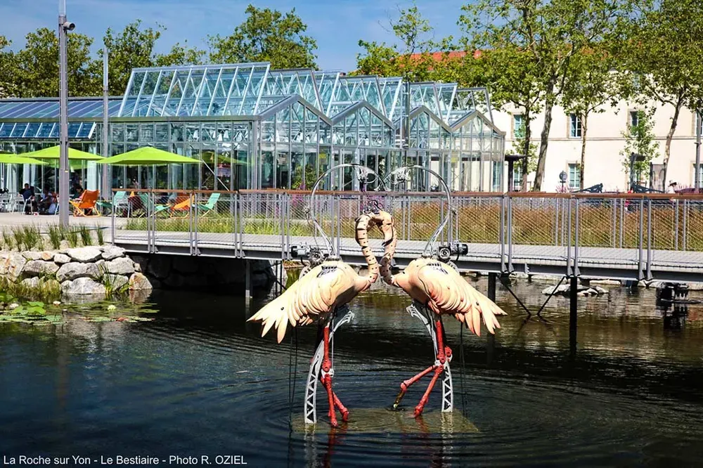Deux flamants roses mécaniques articulés dans un bassin de la place Napoléon à La Roche-sur-Yon.