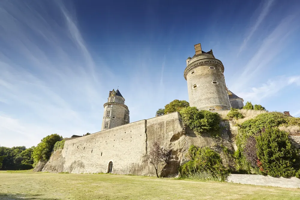 Vue en contre-plongée des deux tours Renaissance et des remparts en pierre du Château d'Apremont sous un ciel bleu